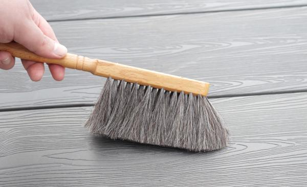 Tischhandfeger mit grauem Ziegenhaar-Besatz. Dieser fegt graues Laminat.